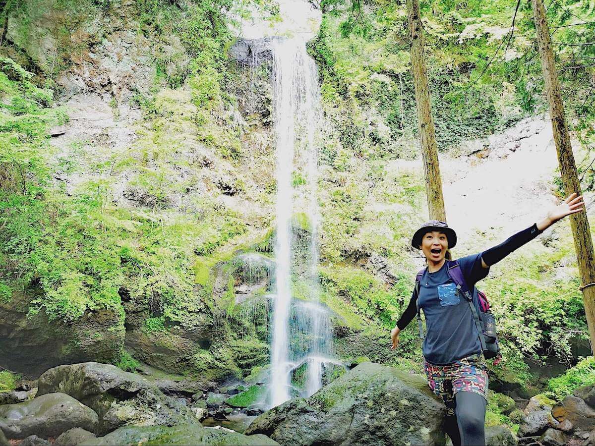 金時山にある「夕日の滝」をバックに記念撮影する高島麻利央さんの写真