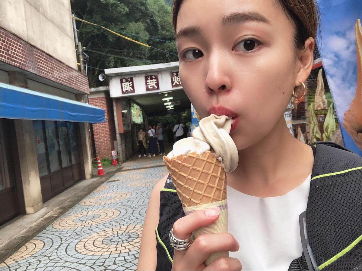 秋芳洞正面入口前でアイスを食べる吉田麻衣子さんの写真
