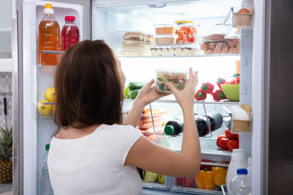 冷蔵庫から食事を選ぶ女性の写真